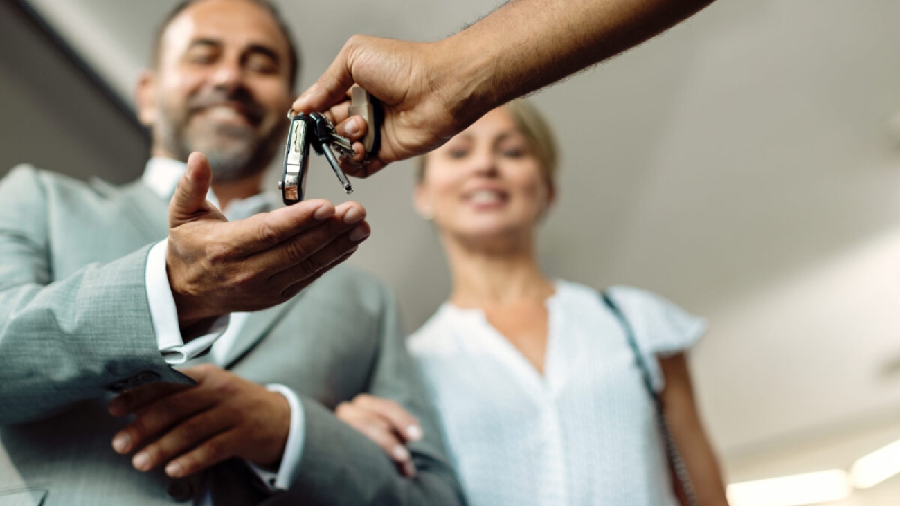Close-up of mechanic giving car keys to a couple in auto repair shop.